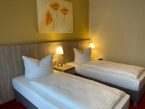 two beds in a hotel room with two lamps at Palm Premium Hotel & Apartments in Düsseldorf