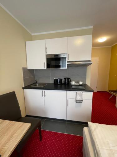 a kitchen with white cabinets and a black counter top at Palm Premium Hotel & Apartments in Düsseldorf
