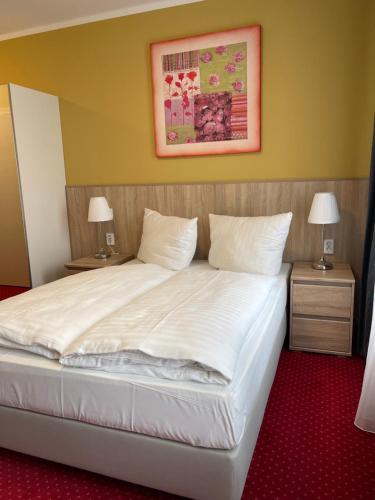 a bedroom with a large white bed with two night stands at Palm Premium Hotel & Apartments in Düsseldorf
