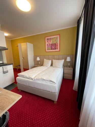 a bedroom with a white bed and red carpet at Palm Premium Hotel & Apartments in Düsseldorf
