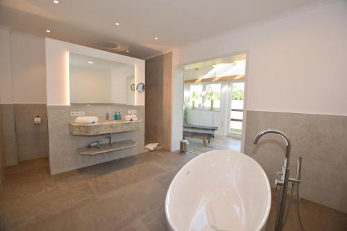 a bathroom with a sink and a bath tub at Landhaus Hideaway mit Aussenpool, Sauna und Kamin in Bosau