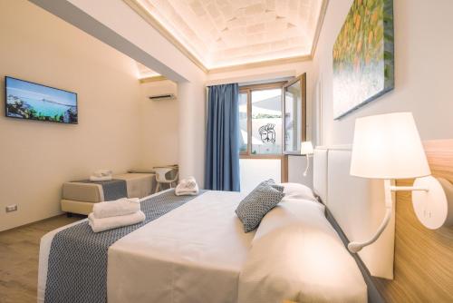 a bedroom with a bed and a lamp and a window at I MORI HOTEL in San Vito lo Capo