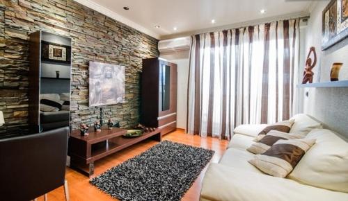 a living room with a white couch and a brick wall at Aquarium House in Sesimbra