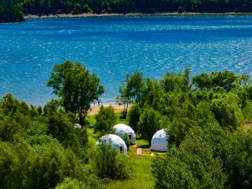 a group of domes in a field next to a body of water at Czorsztyn Glamp in Maniowy