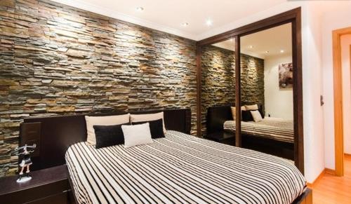 a bedroom with a bed and a stone wall at Aquarium House in Sesimbra