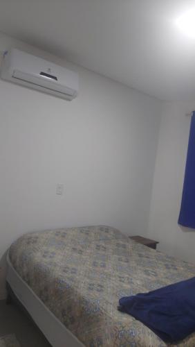a bed in a bedroom with a white wall at Ótimo apartamento sobreloja com wifi e estacionamento incluso in Maringá