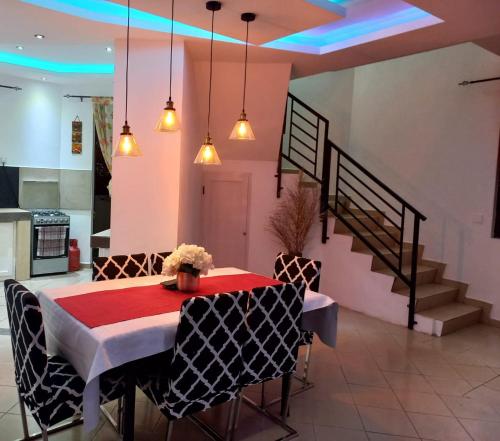 une salle à manger avec une table rouge, des chaises et des escaliers dans l'établissement VILLA L'OR with Private Pool, à Flic-en-Flac