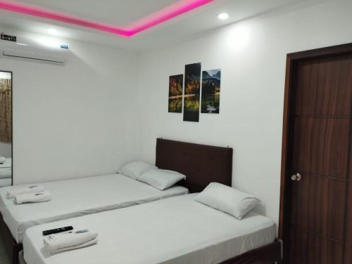 een slaapkamer met 2 bedden en een roze plafond bij Hostal Las Orquideas in Manta