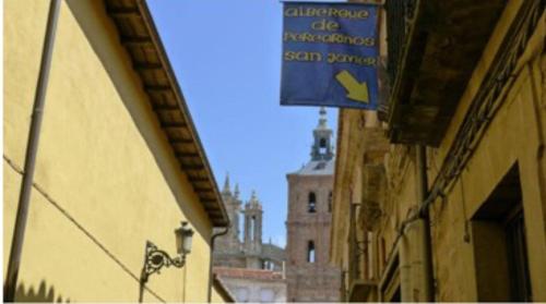 Albergue San Javier - Solo para peregrinos في أستورغا: لوحة زرقاء على جانب مبنى به برج