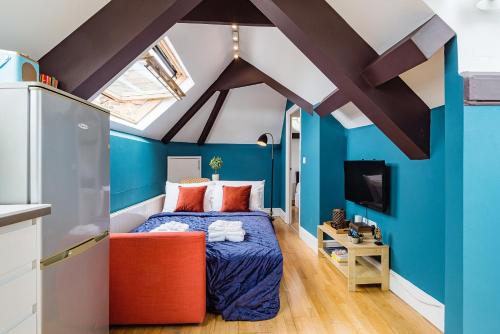 ein Schlafzimmer mit blauen Wänden und einem Bett mit einem orangenen Stuhl in der Unterkunft Sunny Loft in Center of London in London