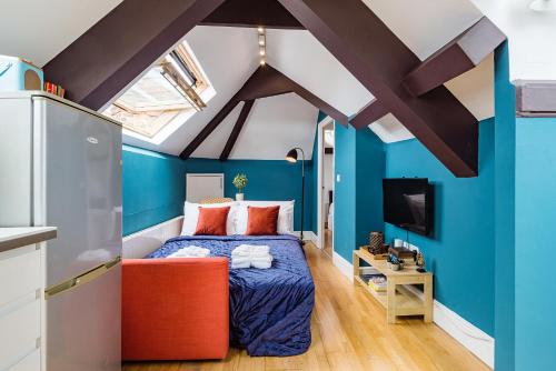 a bedroom with blue walls and a bed with an orange chair at Sunny Loft in Center of London in London