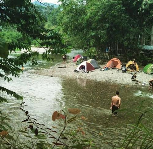 eine Gruppe von Menschen in einem Fluss mit Zelten in der Unterkunft Bukit Lawang Glamping & Jungle Trekking in Bukit Lawang