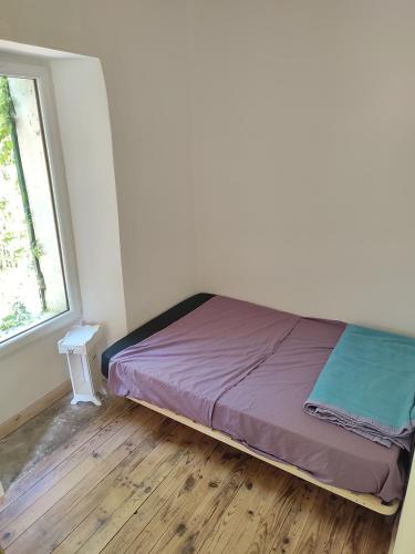 un lit assis dans une pièce avec une fenêtre dans l'établissement L'Aile Ouest en permaculture, à Bergerac