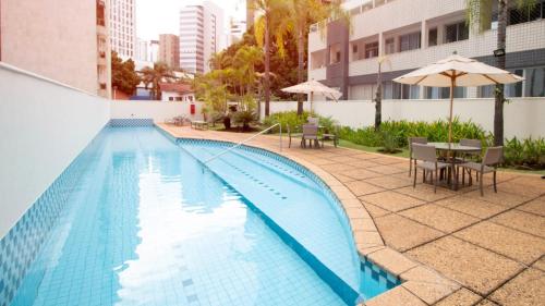 a swimming pool with tables and chairs and an umbrella at Royal Golden Hotel - Savassi in Belo Horizonte