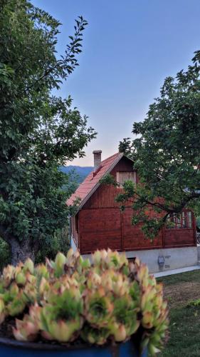 a wooden barn with a house in the background at Apartman Panorama in Mokra Gora