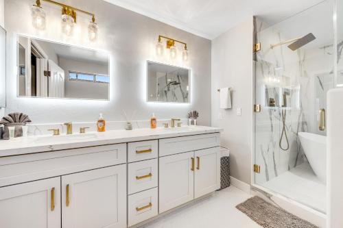 a white bathroom with two sinks and a shower at Desert Dazzle in Peoria