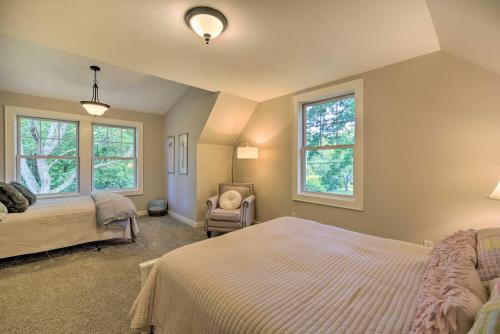 a bedroom with a bed and a chair and two windows at Charming Taylors Falls Home with Deck, Fire Pit in Saint Croix Falls