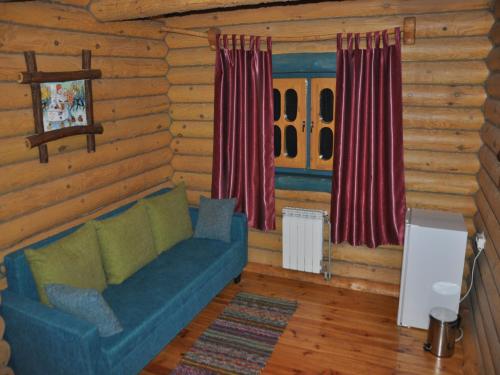 a living room with a blue couch in a log cabin at Gluhoman in Poltava