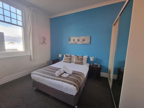 a bedroom with a bed with blue walls and a window at Balcony On Sixth Lodge in Murray Bridge