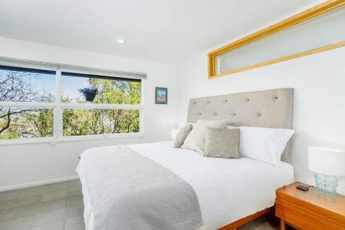 a white bedroom with a large bed and two windows at Downtown Contemporary Coastal Condo in Anchorage
