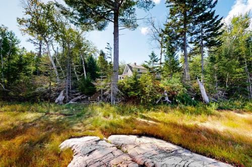 a house in the woods with a rock in the grass at Harbor Myst in Gouldsboro
