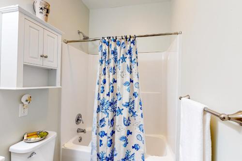 a bathroom with a blue and white shower curtain at Tree Frog KDH920 in Kill Devil Hills