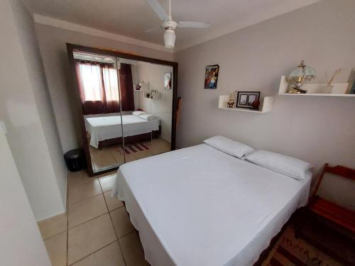 a bedroom with a white bed and a mirror at Apartamento próx ao centro Londrina in Londrina