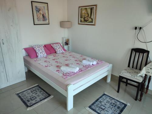 a bedroom with a bed with pink pillows and a chair at Smestaj Vella in Herceg-Novi