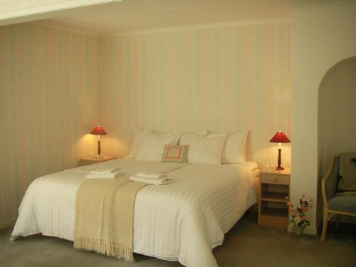 1 dormitorio con 1 cama blanca grande y 2 lámparas en Wilderness Lodge, en Kloten