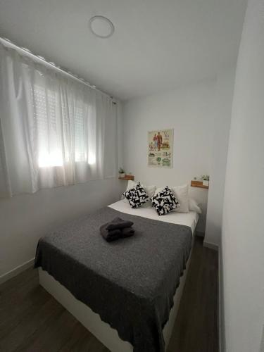 a white bedroom with a bed with a black blanket at Suite by Hawkins Atico in Algeciras