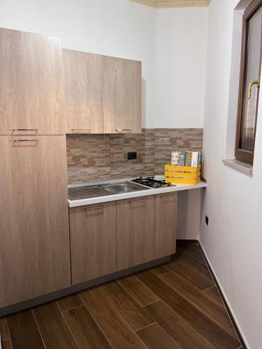 Vibo Apartment في فيبو فالينتيا: مطبخ بدولاب خشبي وفرن علوي موقد