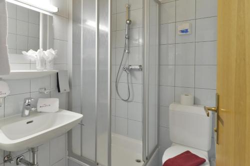 a bathroom with a shower and a toilet and a sink at Hotel Sonnblick in Wald am Arlberg
