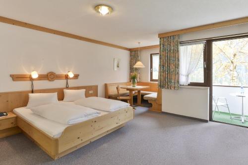 Schlafzimmer mit einem Bett, einem Tisch und einem Fenster in der Unterkunft Hotel Sonnblick in Wald am Arlberg
