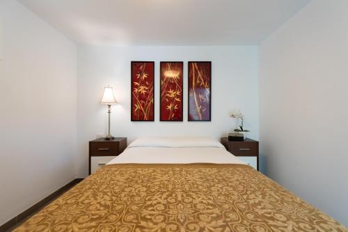 ein Schlafzimmer mit einem Bett und drei Gemälden an der Wand in der Unterkunft Holidays & Health in Finca Oasis - APART 6 in San Roque