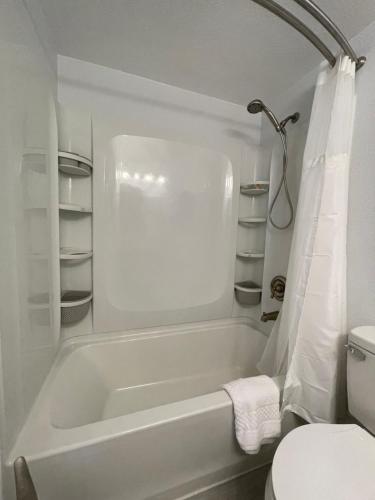 La salle de bains blanche est pourvue d'une baignoire et de toilettes. dans l'établissement Lovely 1 bedroom Condo with pool, à Orlando