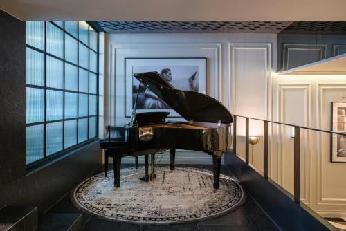 a piano in a room with a window at The Amsterdam by Viadora in Mexico City