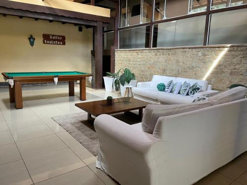 un soggiorno con divani e tavolo da biliardo di Pousada Cozy House a Itaipava