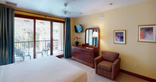 1 dormitorio con 1 cama, 1 silla y balcón en Cascade Village 2 Bedroom Condo, Mere Steps To Chair Lift With Pool And Hot Tubs en Vail