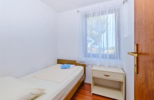 a small bedroom with a bed and a window at Apartments with a parking space Cunski, Losinj - 7867 in Čunski