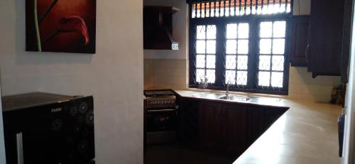a kitchen with a stove and a sink and a window at Wilson Bungalow Kandy in Kandy