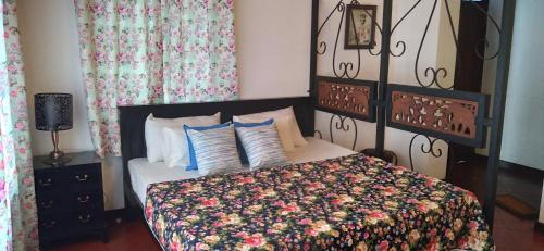 a bedroom with a bed with a floral bedspread at Wilson Bungalow Kandy in Kandy