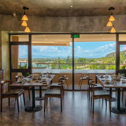 a dining room with tables and chairs and a large window at Ohana Village in Phương Phi