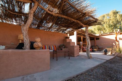 a patio with a straw roof with a couch and a table at Hotel Pat'ta Hoiri in San Pedro de Atacama