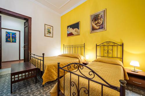 2 letti in una camera da letto con pareti gialle di B&B Casa Degli Artisti a Palermo
