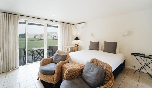 a bedroom with a bed and two chairs and a balcony at Brackenridge Country Retreat & Spa in Martinborough 