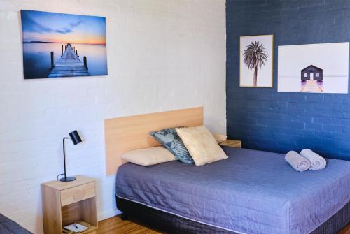 1 dormitorio con cama y pared azul en Mallacoota Hotel Motel, en Mallacoota