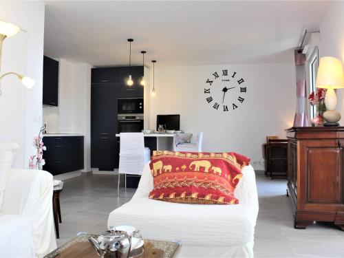 un salon avec un canapé blanc et une horloge au mur dans l'établissement Appartement Neuf 3 Pièces avec Terrasse et Garage, Cagnes-sur-Mer - FR-1-252A-88, à Cagnes-sur-Mer
