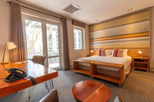 een slaapkamer met een bed, een tafel en een bureau bij Hippo Boutique Hotel in Kaapstad