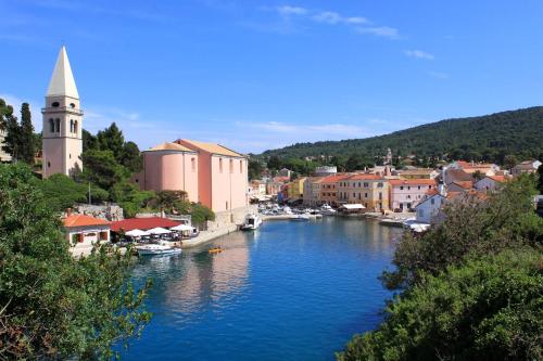 a river with boats in a town with a church at Apartment Veli Losinj 8029b in Veli Lošinj