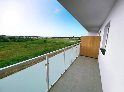 Elle comprend un balcon offrant une vue sur un champ verdoyant. dans l'établissement Elegant 1-Bedroom Flat With Balcony Near Wrocław, à Wrocław